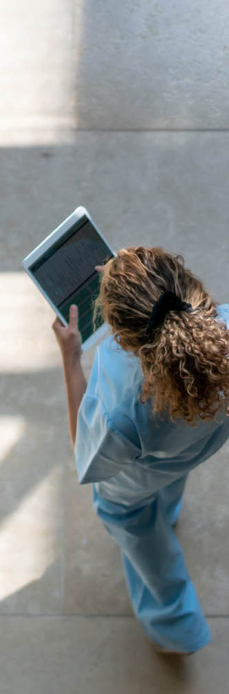 High angle view of nurse walking around hospital while looking at a medical chart on tablet  **DESIGN ON SCREEN WAS MADE FROM SCRATCH BY US**