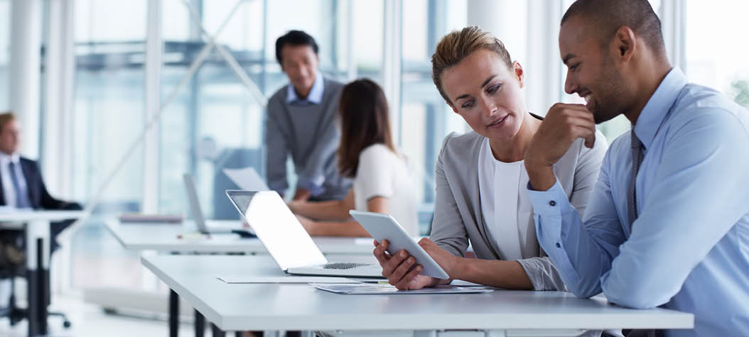 Business colleagues discussing over digital tablet at desk in office
