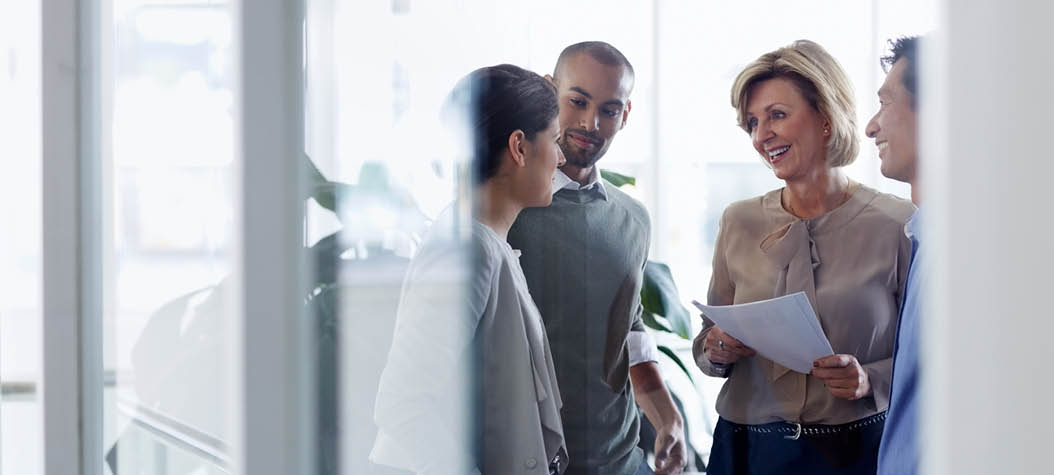 Smiling businesswoman discussing over document with colleagues in office