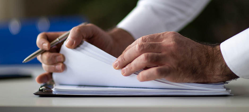 Male arm in suit offer insurance form clipped to pad