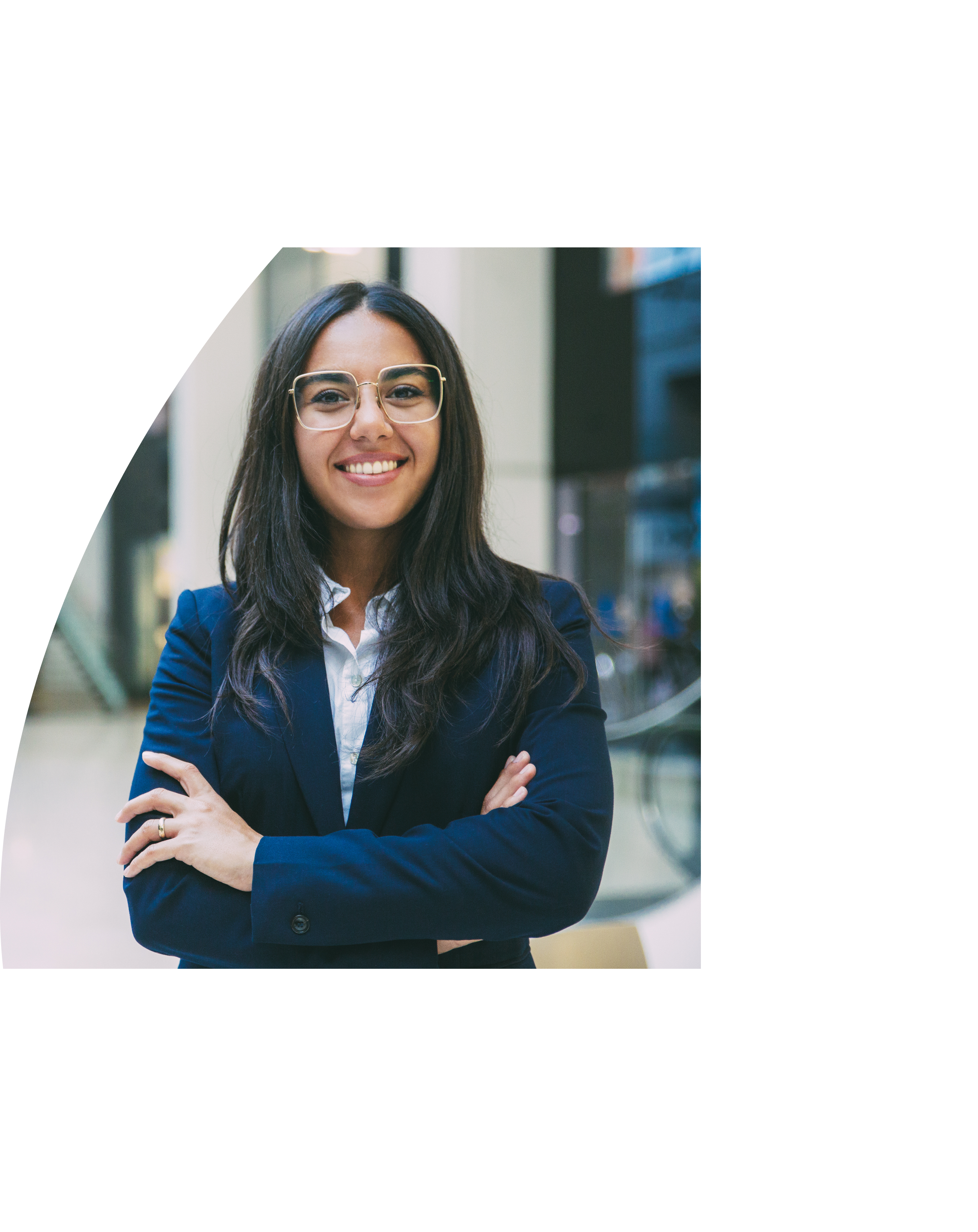 Happy successful businesswoman posing in office hall  Young Latin woman wearing formal suit and glasses, standing for camera with arms folded, smiling  Business portrait concept
